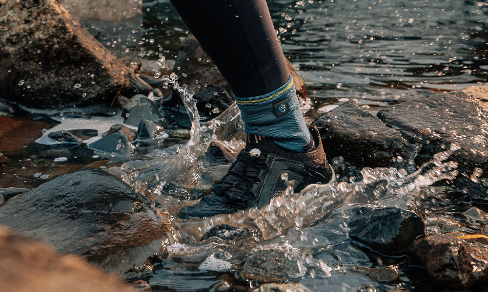 Trail runner across the water splash wearing waterproof running socks